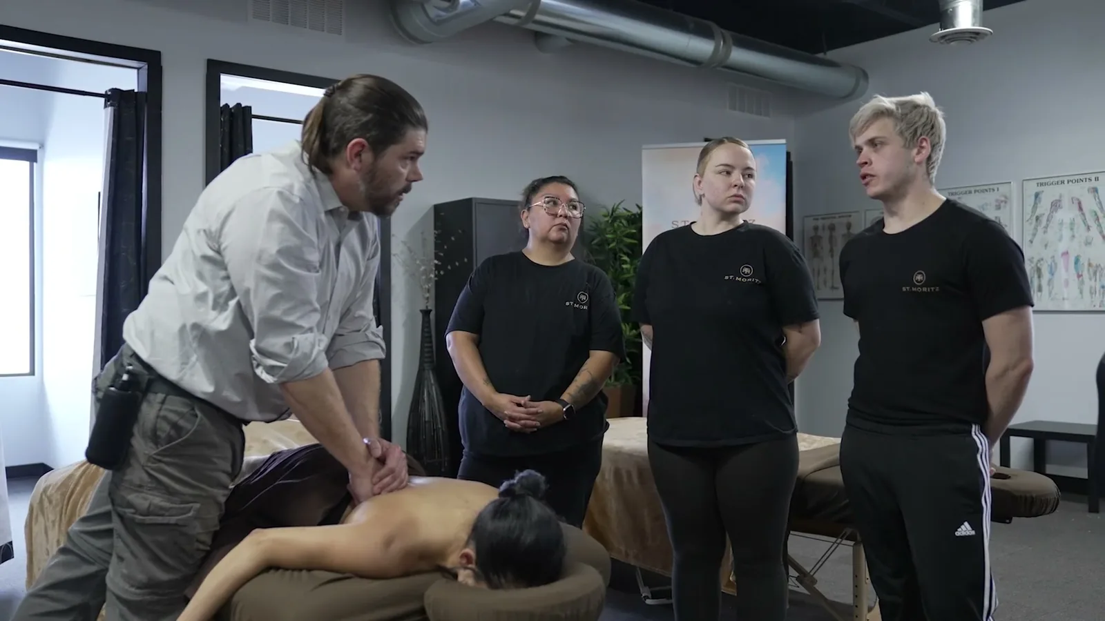 An instructor demonstrating massage technique to a circle of students