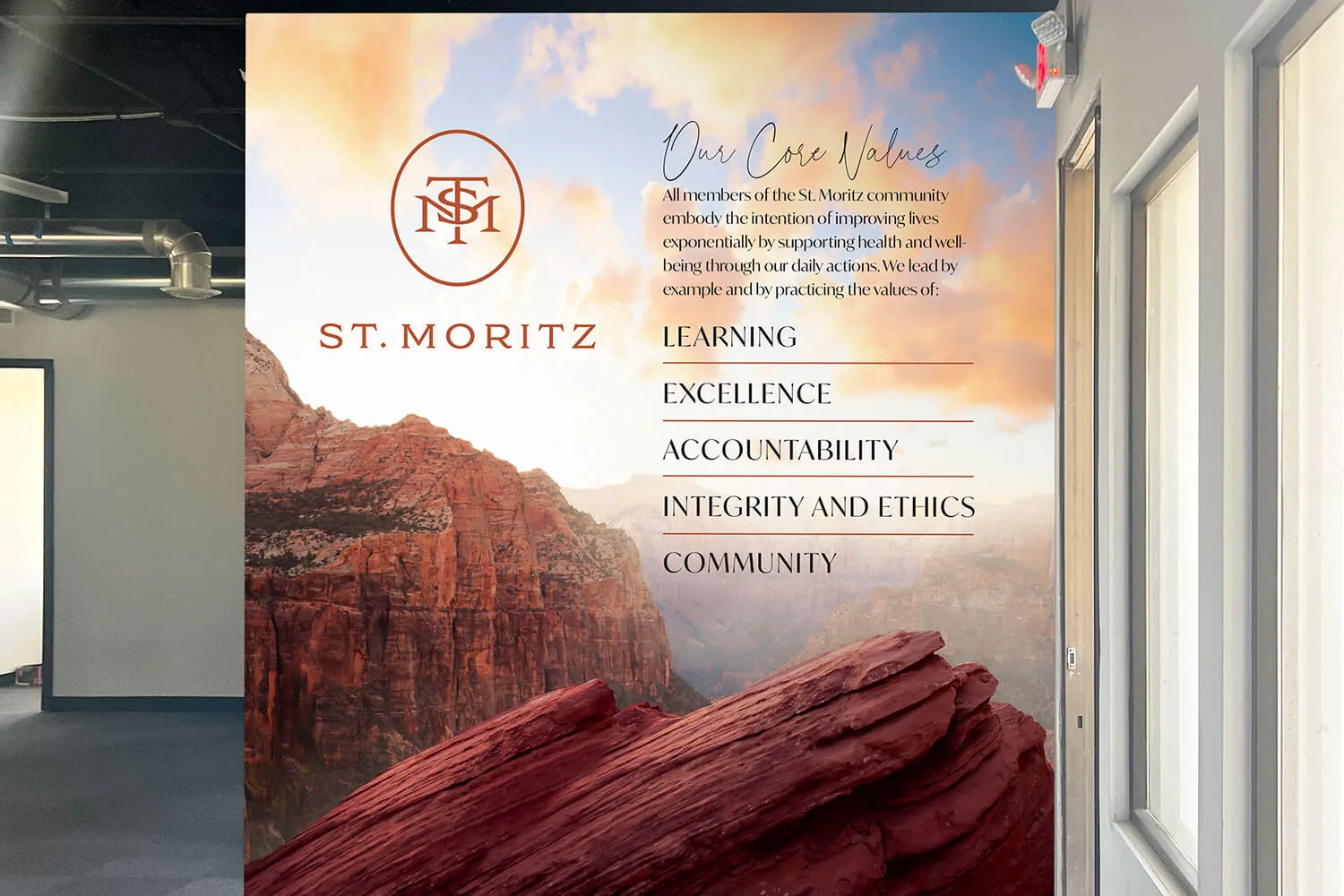The St. Moritz core values mural, set against a red-rock canyon